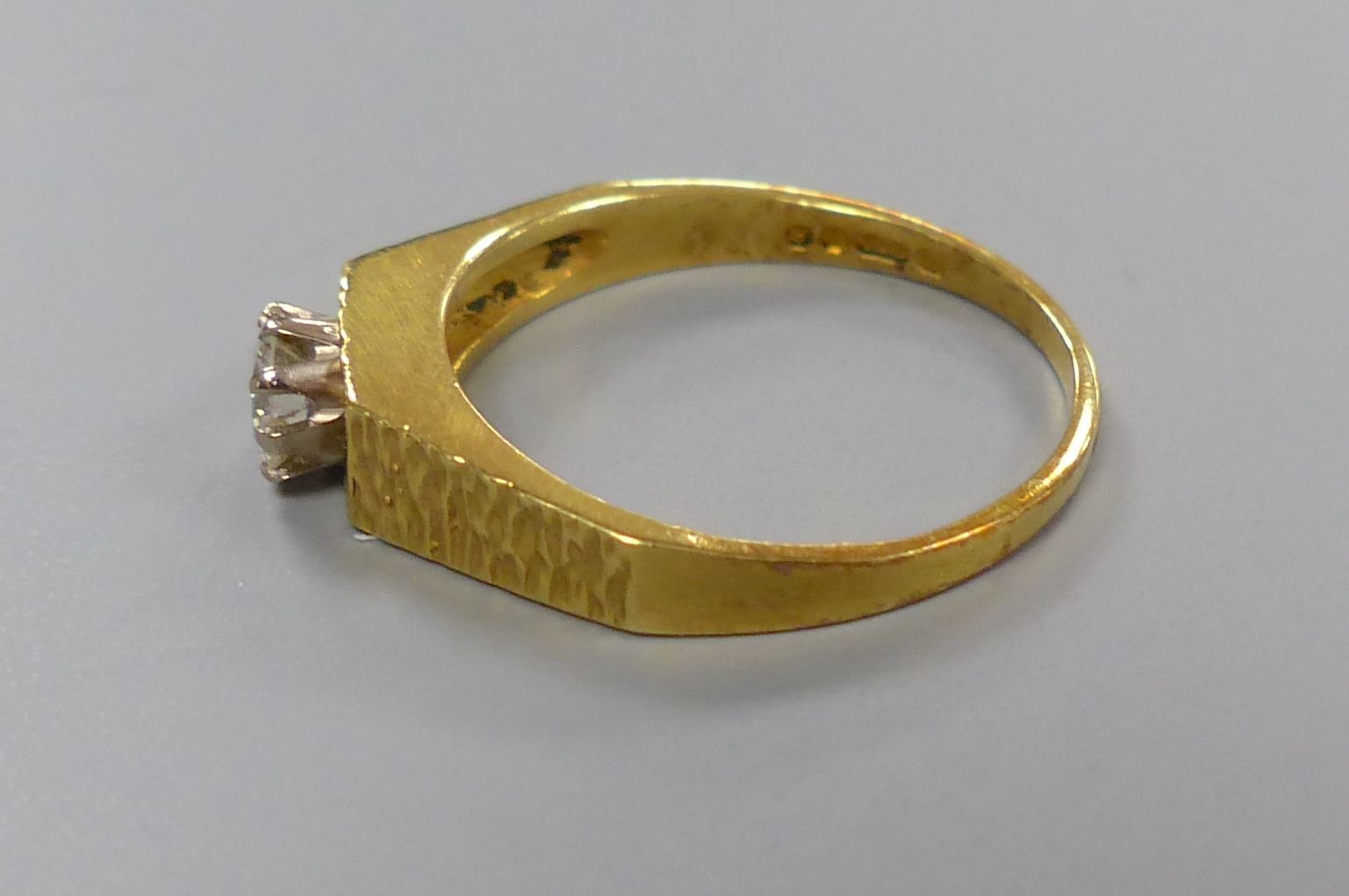 A modern 18ct gold and solitaire diamond ring, with textured shoulders, size N, gross 2.9 grams,